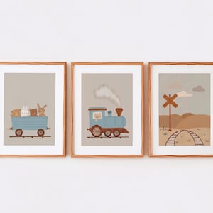May include: Three framed illustrations with a light brown background. The first illustration shows a blue train car with four stuffed animals inside. The second illustration shows a blue train engine with smoke coming from the chimney. The third illustration shows a brown wooden railroad crossing sign with a train track in the background.