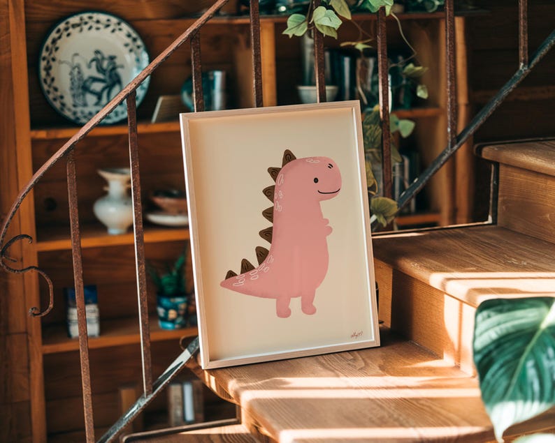 Pu&ograve; includere: Una stampa incorniciata con un'illustrazione di dinosauro rosa con dettagli marroni. Il dinosauro ha un'espressione amichevole ed &egrave; ambientato su uno sfondo color crema. L'opera d'arte &egrave; esposta su una scala di legno.