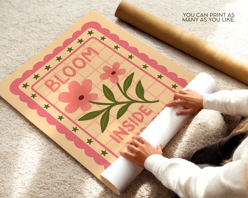 May include: A floral print poster with the words "BLOOM INSIDE" in pink. The poster has a pink scalloped border with green stars. A rolled-up poster and a brown tube are also visible.