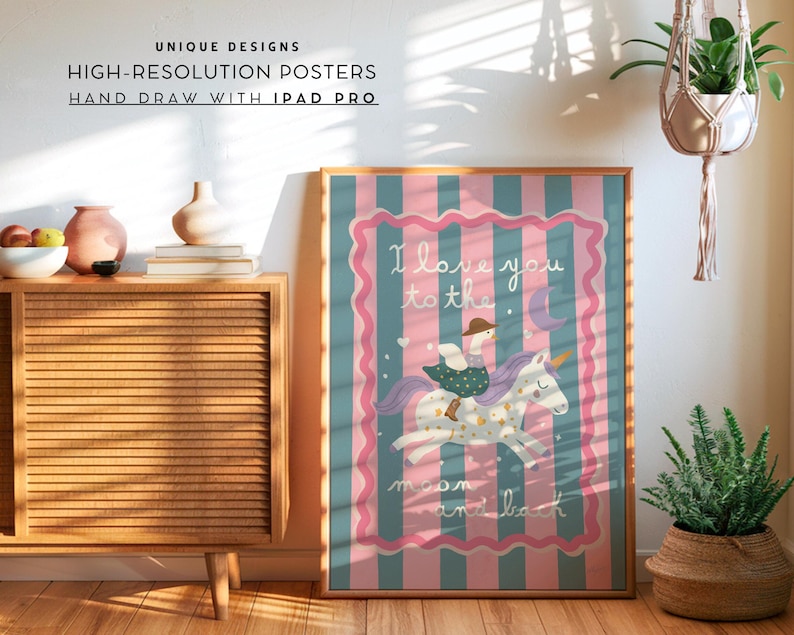 May include: A framed poster with a whimsical illustration of a person riding a unicorn. The artwork features a pink and blue striped background with the text "I love you to the moon and back." The poster is displayed in a room with a wooden cabinet and plants.