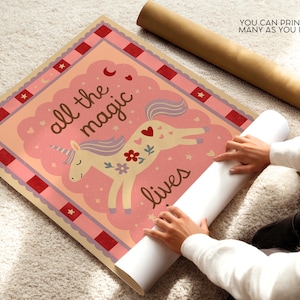 May include: A whimsical poster featuring a unicorn with a floral design and the text "all the magic lives." The poster has a pink and peach color scheme with a red border. A rolled-up poster is next to the poster.