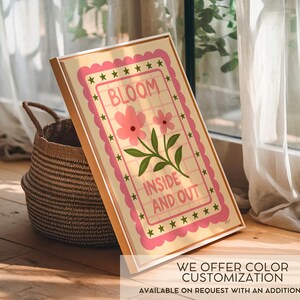 May include: A framed art print with the words "BLOOM INSIDE AND OUT" in a pink and green floral design. The artwork is in a light-colored frame and is propped up next to a woven basket. The text "WE OFFER COLOR CUSTOMIZATION" is at the bottom.