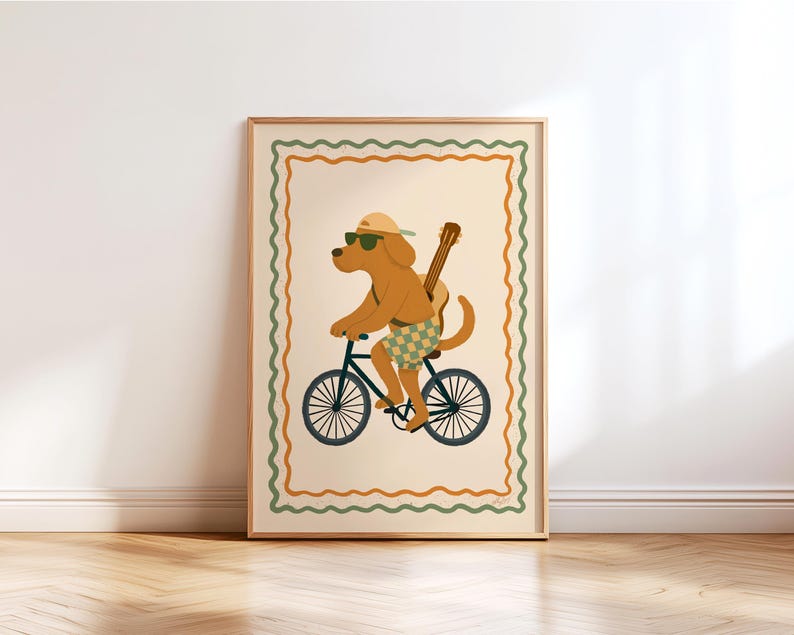 Puede incluir: Una impresión artística enmarcada que presenta un perro de dibujos animados montando en bicicleta. El perro lleva gafas de sol, una gorra y pantalones cortos, con una guitarra en la espalda. La obra de arte tiene un fondo crema con un borde decorativo verde y naranja.