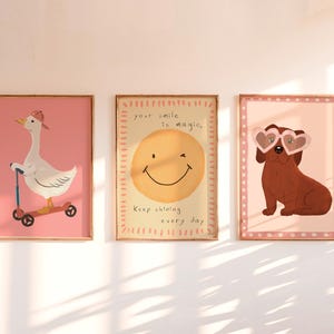 Pu&ograve; includere: Tre stampe artistiche incorniciate con un tema stravagante. Uno presenta un'oca su uno scooter, un altro una faccia sorridente con testo e l'ultimo un cane con occhiali da sole a forma di cuore. Ogni stampa ha uno sfondo rosa.