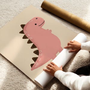 Pu&ograve; includere: Illustrazione di un dinosauro rosa su un poster beige. Il dinosauro ha un'espressione amichevole e spine marroni sulla schiena. Sono visibili anche un poster arrotolato e un tubo marrone.