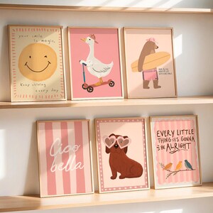 Pu&ograve; includere: Una collezione di stampe artistiche incorniciate con illustrazioni stravaganti. Le stampe includono un sole sorridente, un'oca su uno scooter, un orso con una tavola da surf, un cane con occhiali a forma di cuore e citazioni ispiratrici. La tavolozza dei colori &egrave; rosa e giallo tenui.