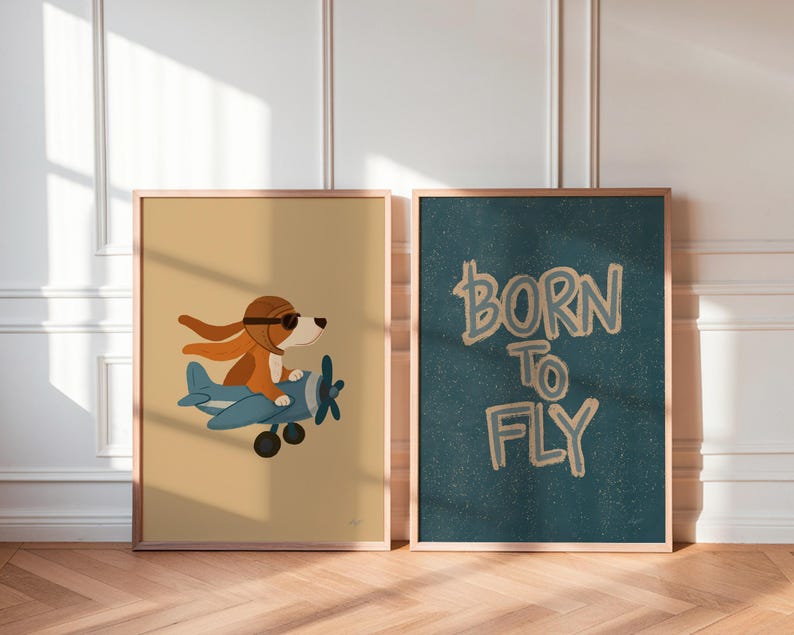 May include: Two framed wall art prints. The left print features a brown dog wearing a brown aviator cap and goggles, piloting a blue airplane against a tan background. The right print displays the text BORN TO FLY in tan on a dark teal background.