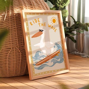 K&ouml;nnte beinhalten: Eine gerahmte Illustration eines Pelikans mit Sonnenbrille, der auf einem Surfbrett auf einer Welle reitet. Der Text "Ride the Wave" steht &uuml;ber dem Pelikan.