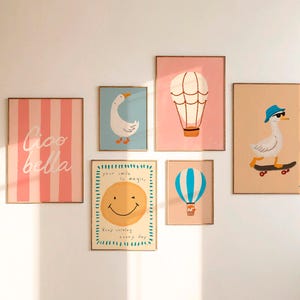 May include: A collection of framed art prints featuring whimsical illustrations. The prints include a pink striped design with the words "Ciao Bella", a goose, hot air balloons, and a smiley face with the text "Your smile is magic".