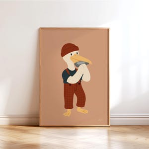 May include: A framed art print featuring a cartoon pelican playing a harmonica. The pelican wears a brown beanie, a navy blue shirt, and red plaid overalls. The background is a solid peach color, and the frame is a light brown.
