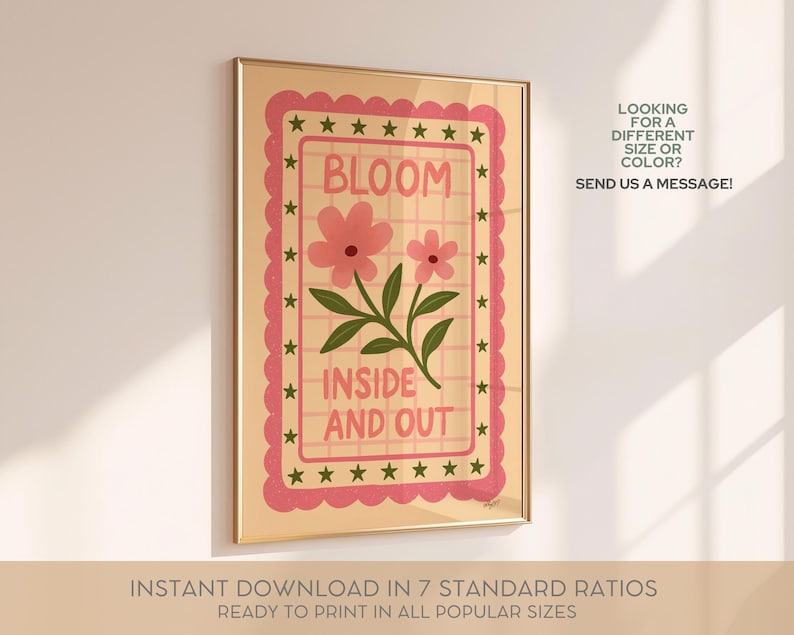 May include: A framed art print with a floral design. The artwork features the word "BLOOM" above two pink flowers and the phrase "INSIDE AND OUT". The print has a pink scalloped border with stars and is in a gold frame.