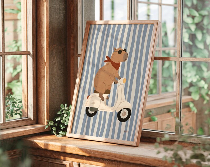 framed capybara scooter poster leaning against molded wall with tropical plant coastal kids room decor blue stripe nursery art