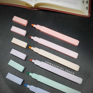 May include: Set of eight pastel highlighters with matching caps. The highlighters are in shades of pink, beige, lavender, green, and blue. The text "UNWAVERING GRACE" is printed on one of the highlighters.
