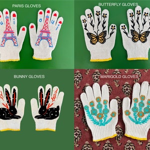 May include: Four pairs of white cotton work gloves with different embroidered designs. The designs include a Parisian Eiffel Tower, butterflies, a bunny rabbit, and marigolds.