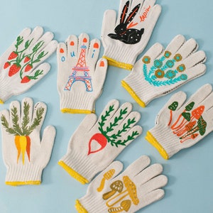 May include: Set of 8 white cotton gardening gloves with colorful hand-painted designs. The designs include strawberries, a carrot, a radish, mushrooms, a bunny, flowers, and the Eiffel Tower with the word "oui".