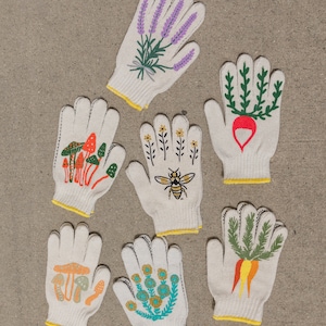 May include: Set of six white cotton gardening gloves with different floral and nature-themed designs. The designs include lavender, a bee, mushrooms, carrots, and flowers.