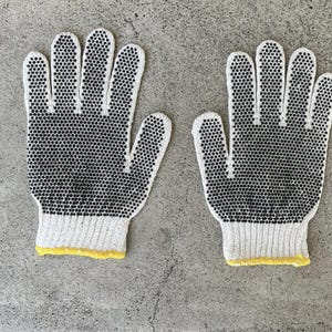 May include: Pair of white work gloves with black dotted grips. The gloves have a ribbed cuff with a yellow trim. The gloves are designed for protection and grip, suitable for various tasks.