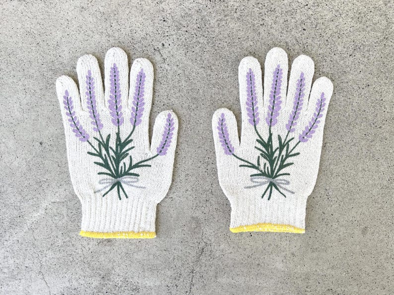 May include: A pair of white knitted gloves with a lavender floral design. The gloves feature purple lavender sprigs with green leaves and stems, tied with a gray bow. The cuffs have a yellow trim.