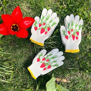 May include: Three pairs of white gardening gloves with a strawberry design. The gloves have yellow trim around the wrist.