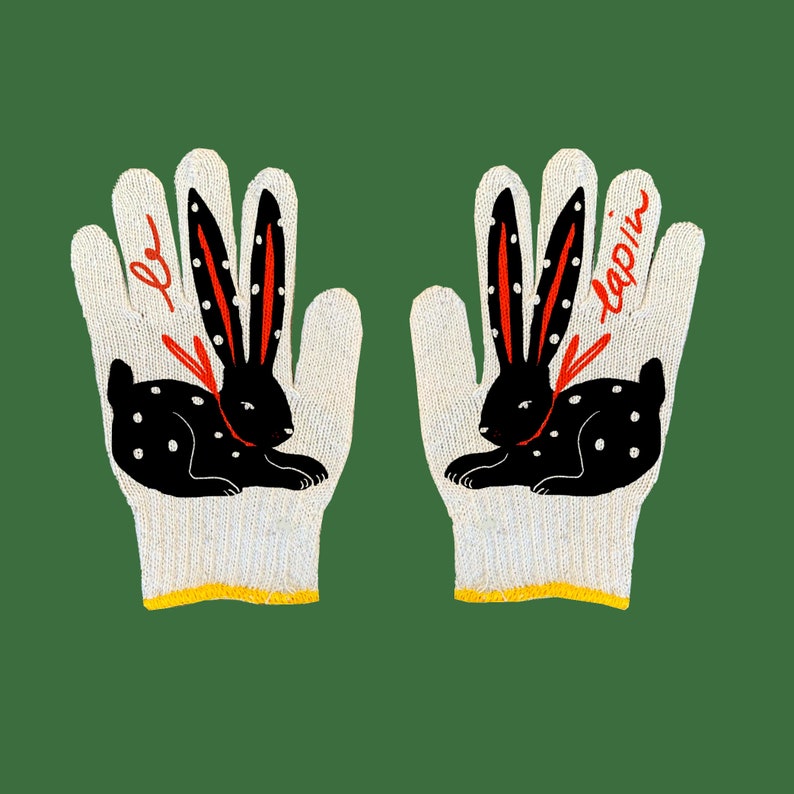 May include: A pair of white knit gloves with black and red bunny illustrations. The left glove has the word "lapin" written on it.