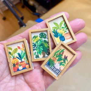 May include: Four miniature framed art pieces featuring colorful illustrations of potted plants. Each frame has a gold-painted border. The artwork includes various plant species and decorative pots, with a focus on botanical themes.