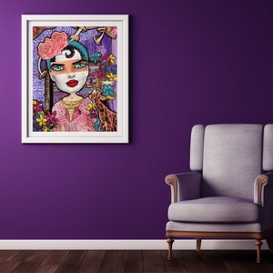 May include: A colorful mixed media painting of a woman with a pink flower crown and a giraffe. The woman is wearing a pink dress and has blue eyes and red lips. The painting is framed in white and has the text "Pretty, Tough, Brave" written on it.