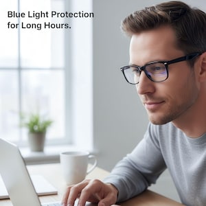 May include: A man wearing black-framed glasses with clear lenses, typing on a laptop. The text "Blue Light Protection for Long Hours" is displayed at the top of the image. The man is wearing a gray long-sleeve shirt.