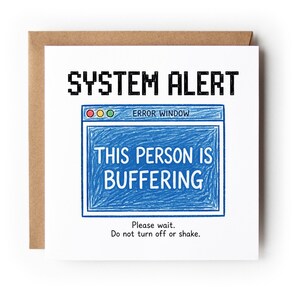 May include: A square greeting card with a white background featuring the black text SYSTEM ALERT at the top. Below is a blue crayon-style error window graphic with the text THIS PERSON IS BUFFERING. Below the window is the text Please wait. Do not turn off or shake.