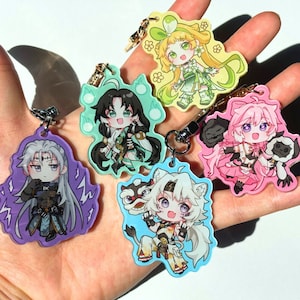 May include: A selection of anime-style character keyrings in various colours. Each keyring showcases a unique character design with bright colours and intricate details. The keyrings have metal clasps for easy attachment.