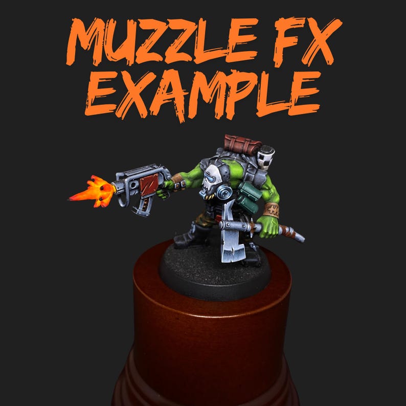 May include: A miniature green figure with a gas mask and a weapon, firing a flame. The figure is on a wooden base, with the words "MUZZLE FX EXAMPLE" in orange above. The figure is holding a gun with red accents.