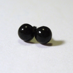 Puede incluir: Dos ojos de muñeca de plástico negro con un vástago de metal.
