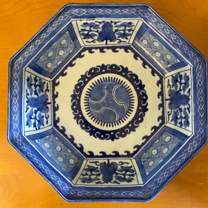 May include: Octagonal blue and white porcelain serving dish with a geometric pattern and floral designs. The center of the dish features a blue and white circle with a stylized design.