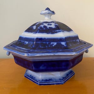 May include: Octagonal blue and white porcelain serving dish with a lid. The dish has a raised base and a decorative knob on the lid.