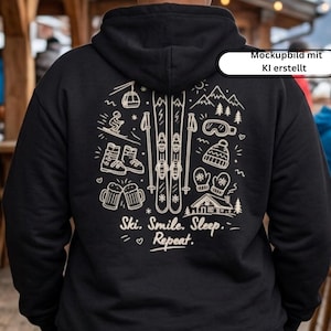 Könnte beinhalten: Ein schwarzer Kapuzenpullover mit einer weißen Strichgrafik auf der Rückseite. Das Design zeigt Skier, Stöcke, einen Skilift, eine Skibrille, eine Mütze, Fäustlinge, Bierkrüge und eine Hütte. Der Text lautet: Ski. Smile. Sleep. Repeat.