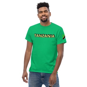 May include: A green t-shirt with the word "TANZANIA" printed in yellow and black letters. The right sleeve has a small image of the Tanzanian flag.