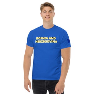 May include: A royal blue t-shirt with the text "BOSNIA AND HERZEGOVINA" in yellow letters. The shirt has a small Bosnian flag on the right sleeve.