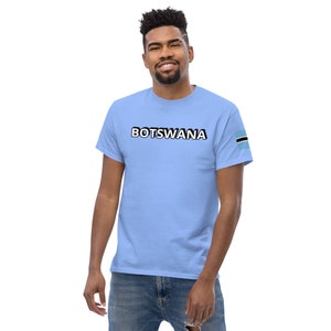 May include: A light blue t-shirt with the word "BOTSWANA" printed in black on the front. The right sleeve has a small, black and blue flag of Botswana.