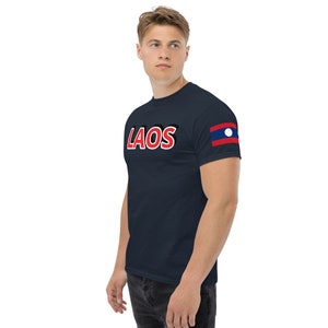 May include: A navy blue t-shirt with the word "LAOS" in red and black lettering. The shirt has a small flag of Laos on the right sleeve.