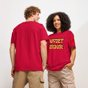 May include: Red t-shirts with the text "SOVIET UNION" in yellow and black lettering. The t-shirts also feature a small red flag with a gold star. The models are wearing khaki cargo shorts.