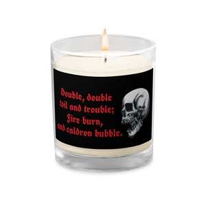May include: A black and white skull candle with a red inscription that reads "Double, double toil and trouble; Fire burn, and caldron bubble."