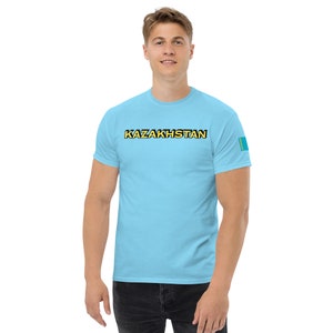 May include: A light blue t-shirt with the word "KAZAKHSTAN" printed in black with yellow outlines. The right sleeve has a small patch with the flag of Kazakhstan.