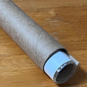 May include: A rolled up poster or print with a brown paper tube and a white backing. The poster is wrapped in clear plastic.