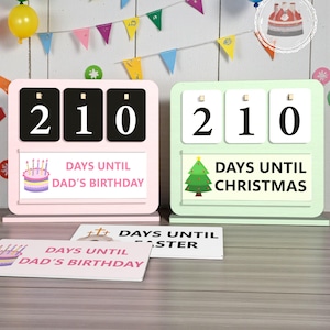 May include: Two countdown calendars, one pink and one green, displaying the number 210. The pink calendar reads "Days Until Dad's Birthday" and has a cake illustration. The green calendar reads "Days Until Christmas" with a Christmas tree.