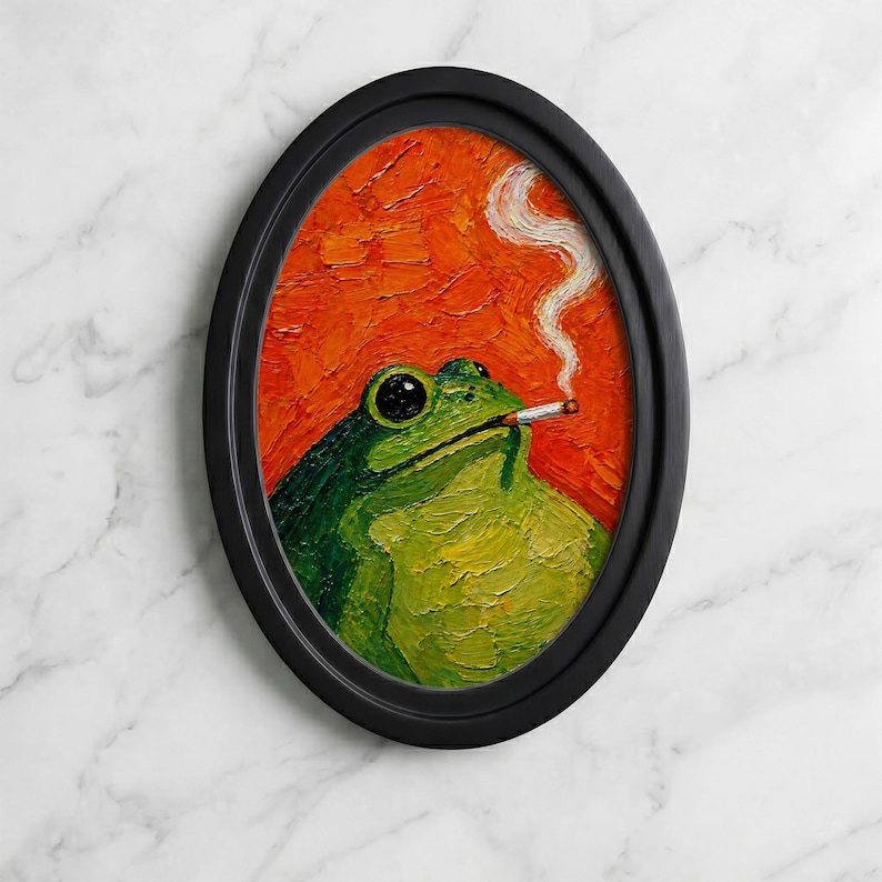 May include: An oval-framed oil painting featuring a green frog with a textured, impasto finish. The frog is depicted with a cigarette in its mouth, with a thin trail of white smoke rising against a vibrant, solid orange background.