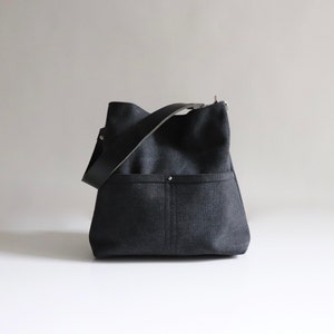 Black hobo bag with two front pockets  and a wide leather shoulder strap.  Medium size hobo purse in black canvas.