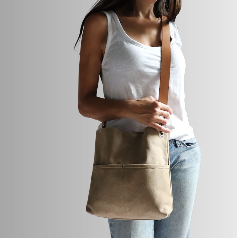 Medium size canvas hobo bag worn crossbody style shown on model in jeans and white tank top..