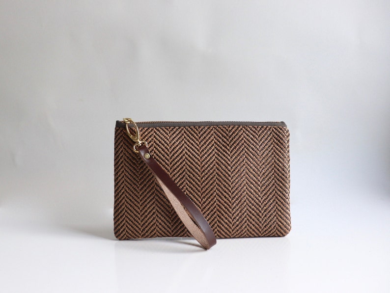 May include: A brown and black herringbone clutch with a brown leather strap.