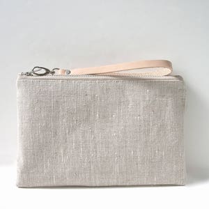 Handcrafted linen wristlet purse in natural, oat color with natural leather wrist strap and a zippered closure.