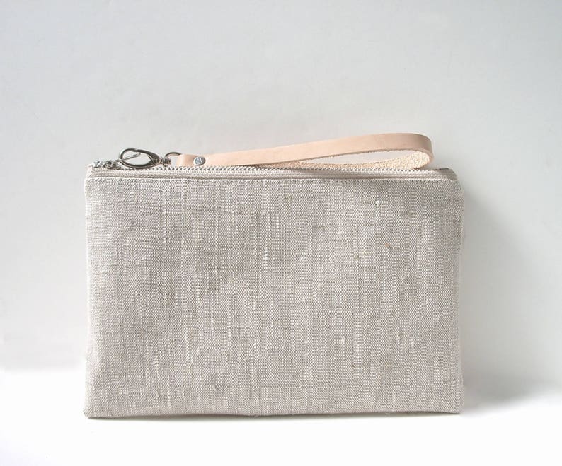 Handcrafted linen wristlet purse in natural, oat color with natural leather wrist strap and a zippered closure.