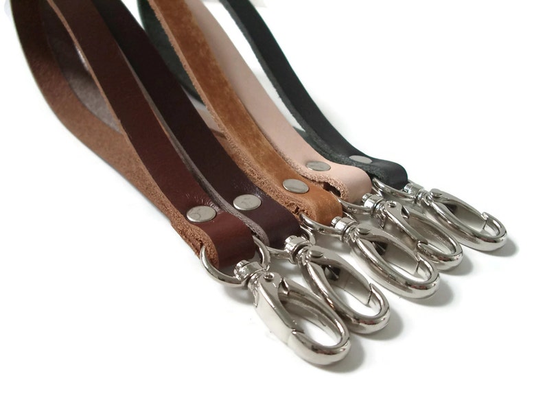 May include: Five leather keychains in different colors, including brown, tan, black, and cream, with silver swivel clips.